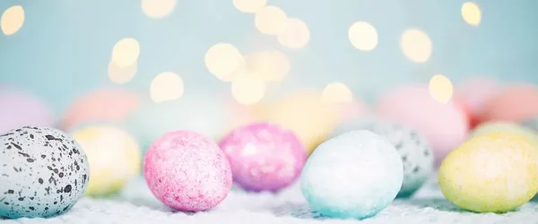 Pastelkleurige gespikkelde paaseieren voor een lichtblauwe achtergrond