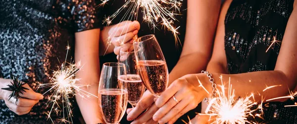 Handen die klinken met champagneglazen tussen brandende sterretjes